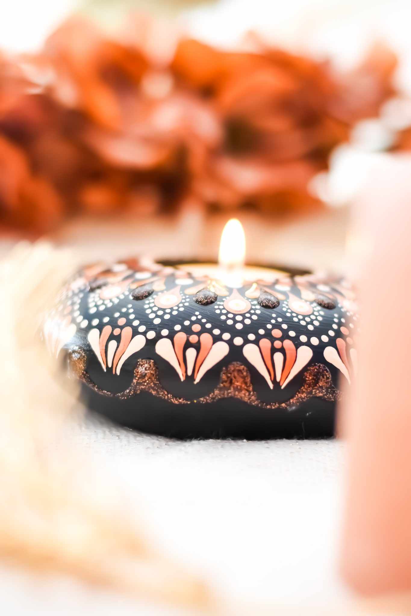 bougeoir fait main avec mandala rose et doré sur fond noir contenant une bougie.