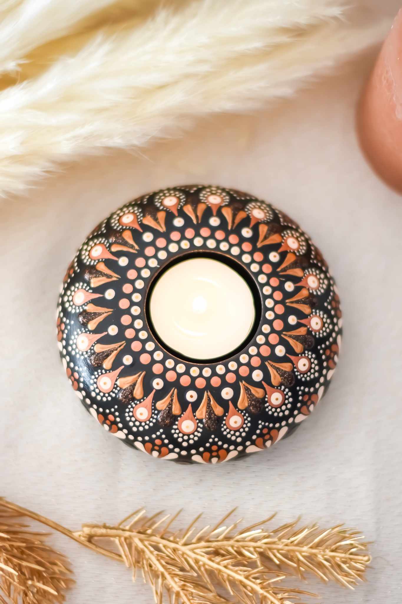 bougeoir fait main avec mandala rose et doré sur fond noir contenant une bougie.